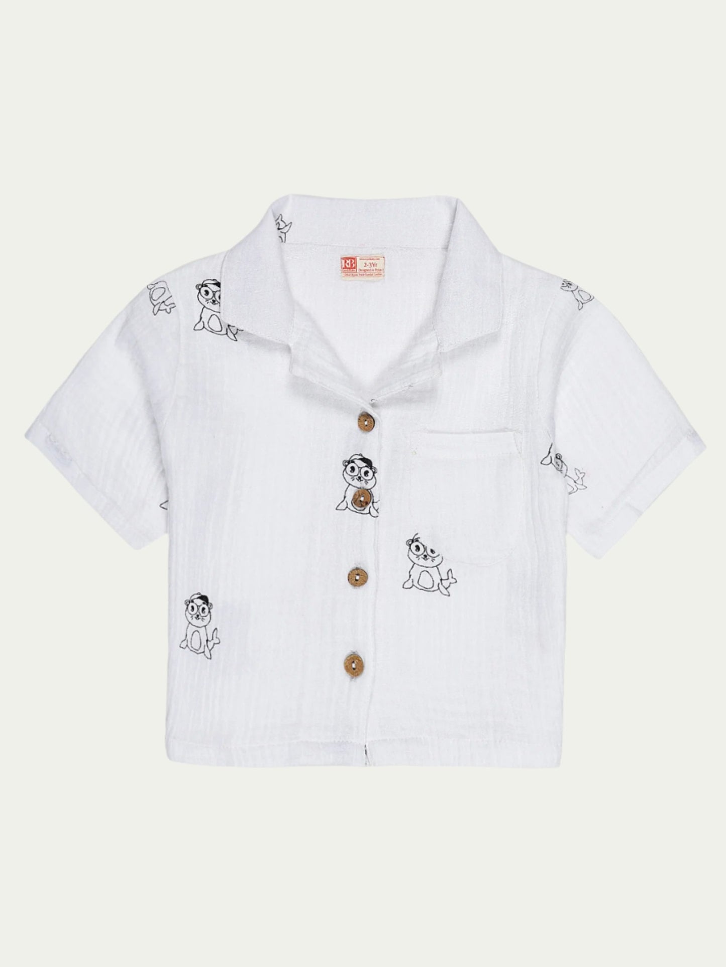 Front view of white organic cotton baby shirt with short sleeves, wooden buttons, front pocket, and playful cartoon print – designed for babies aged 0-3 years by Ray&Baby.