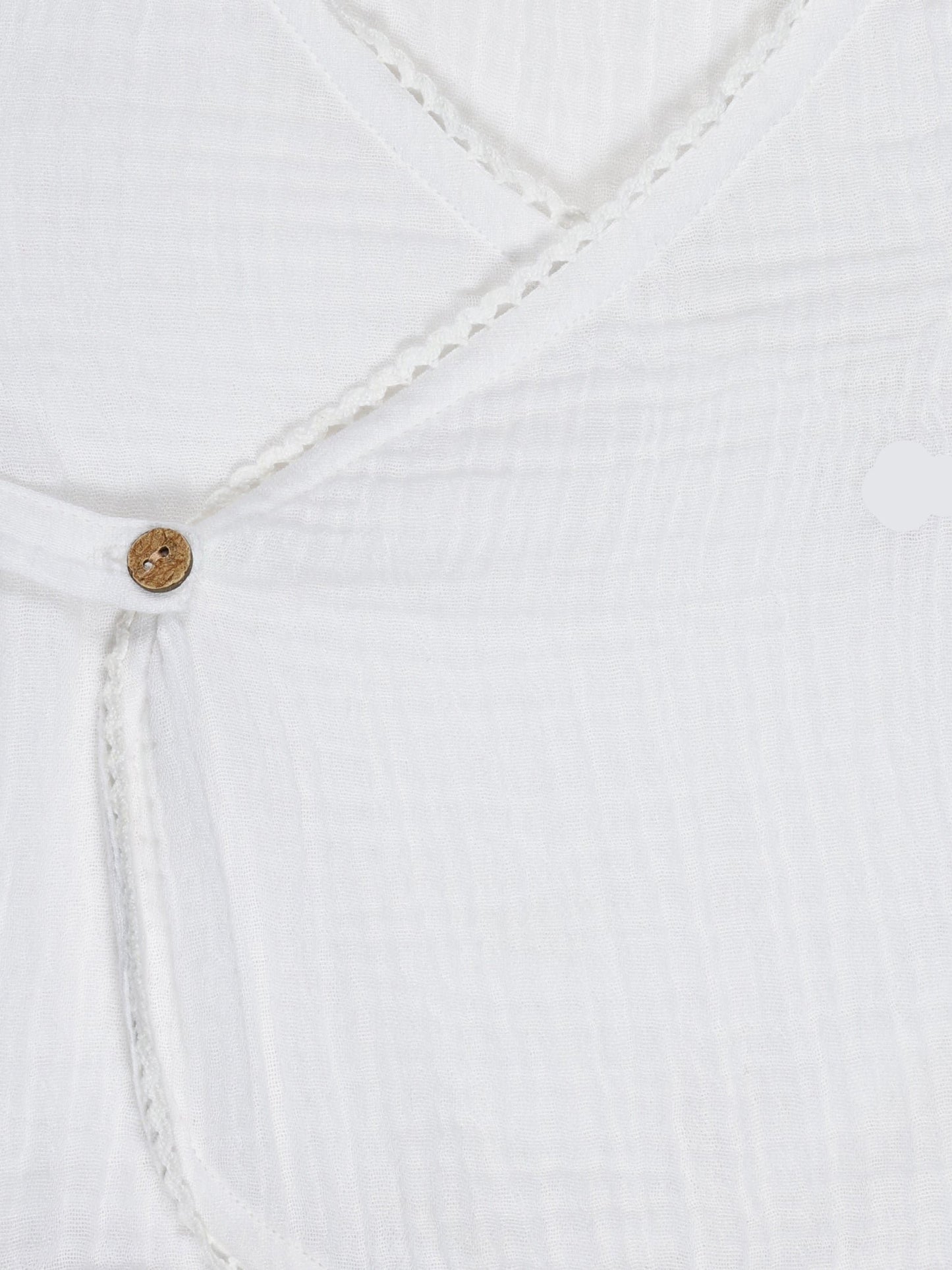 Close-up of wooden button and lace trim on white organic cotton baby wrap shirt – breathable and eco-friendly fabric by Ray&Baby.