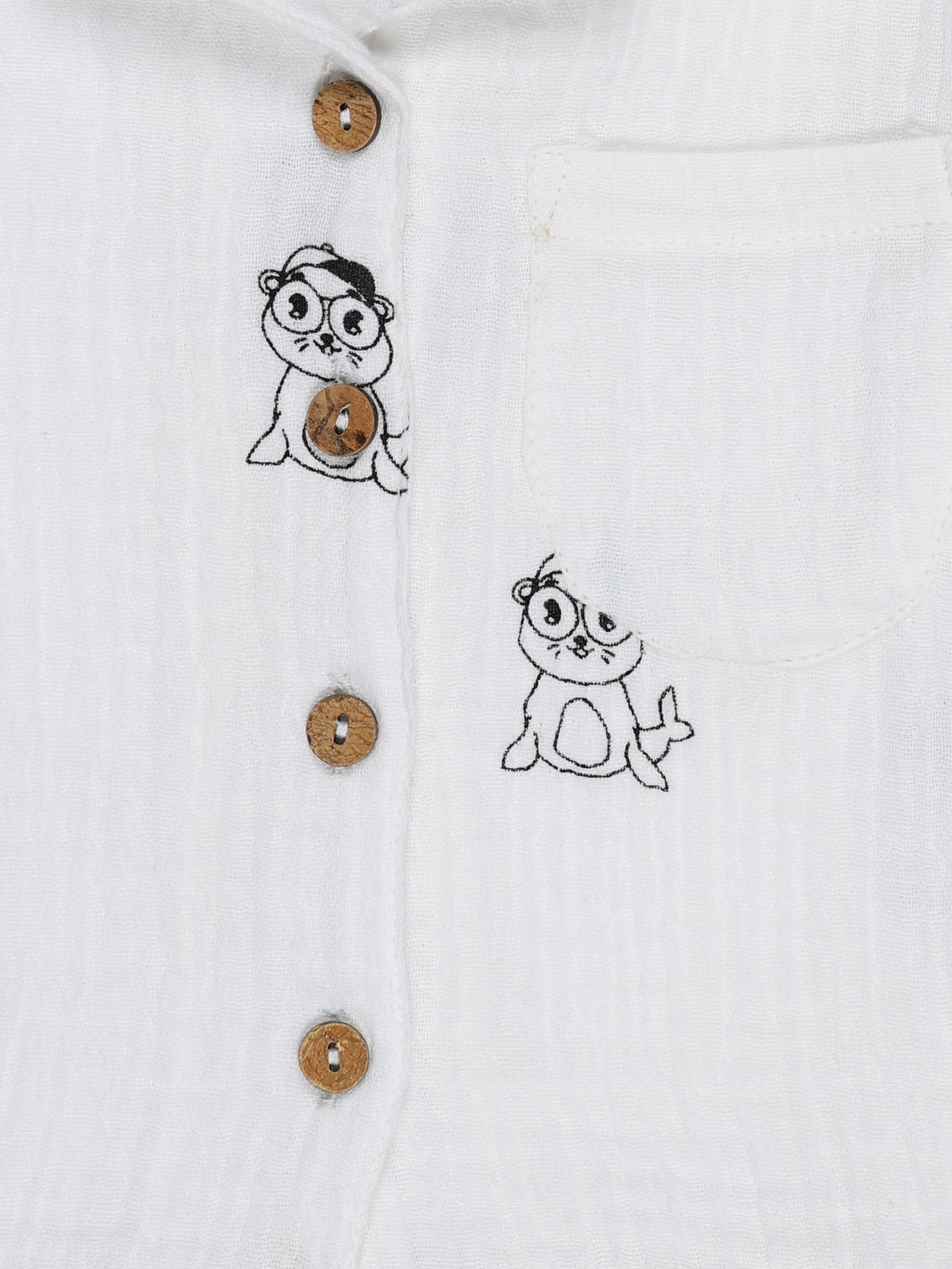 Close-up of wooden buttons and cartoon print on white organic cotton baby shirt – soft, breathable fabric, ideal for babies aged 0-3 years by Ray&Baby.