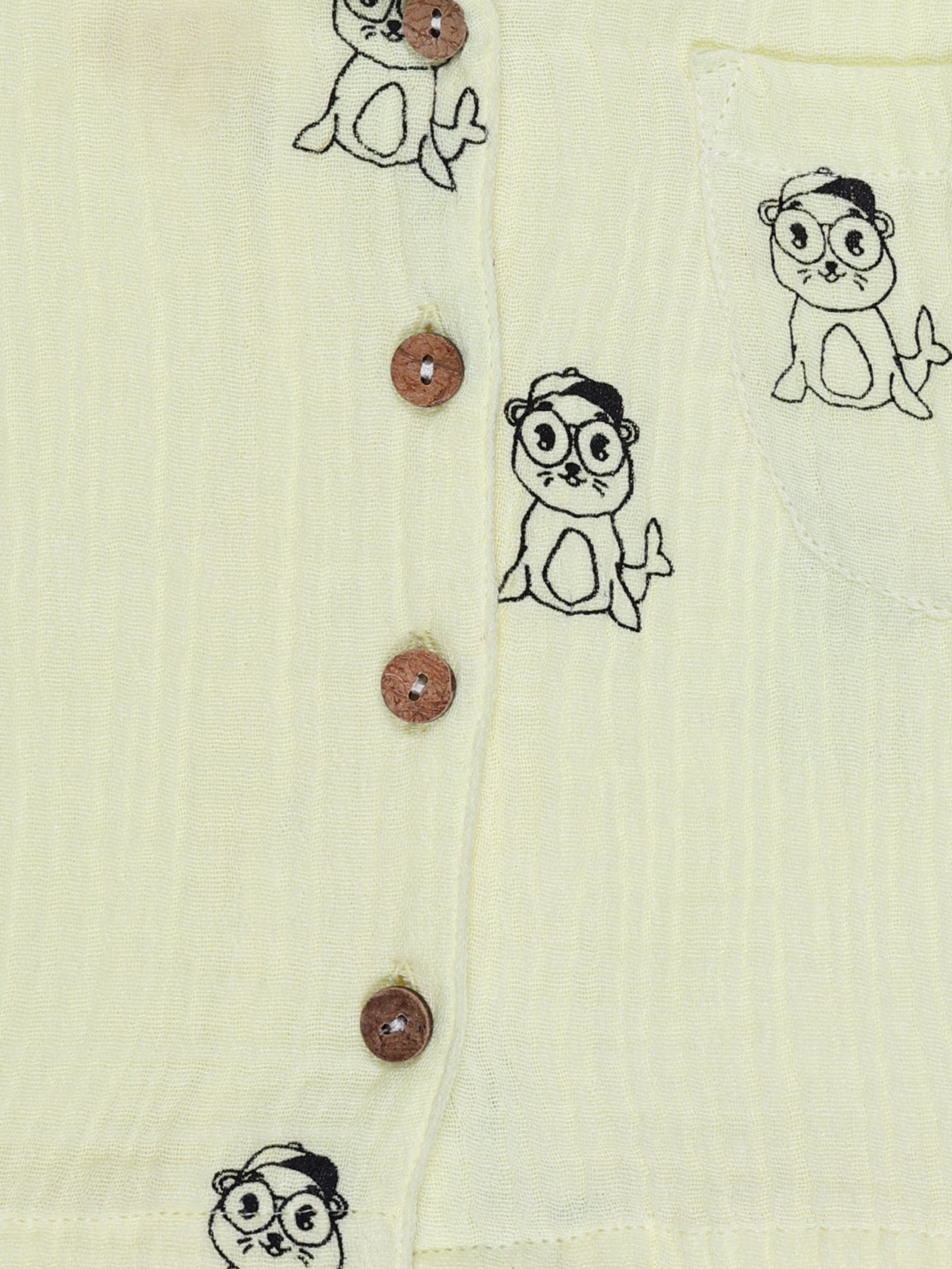 Close-up of wooden buttons and seal print on yellow organic cotton baby shirt – breathable and eco-friendly by Ray&Baby.