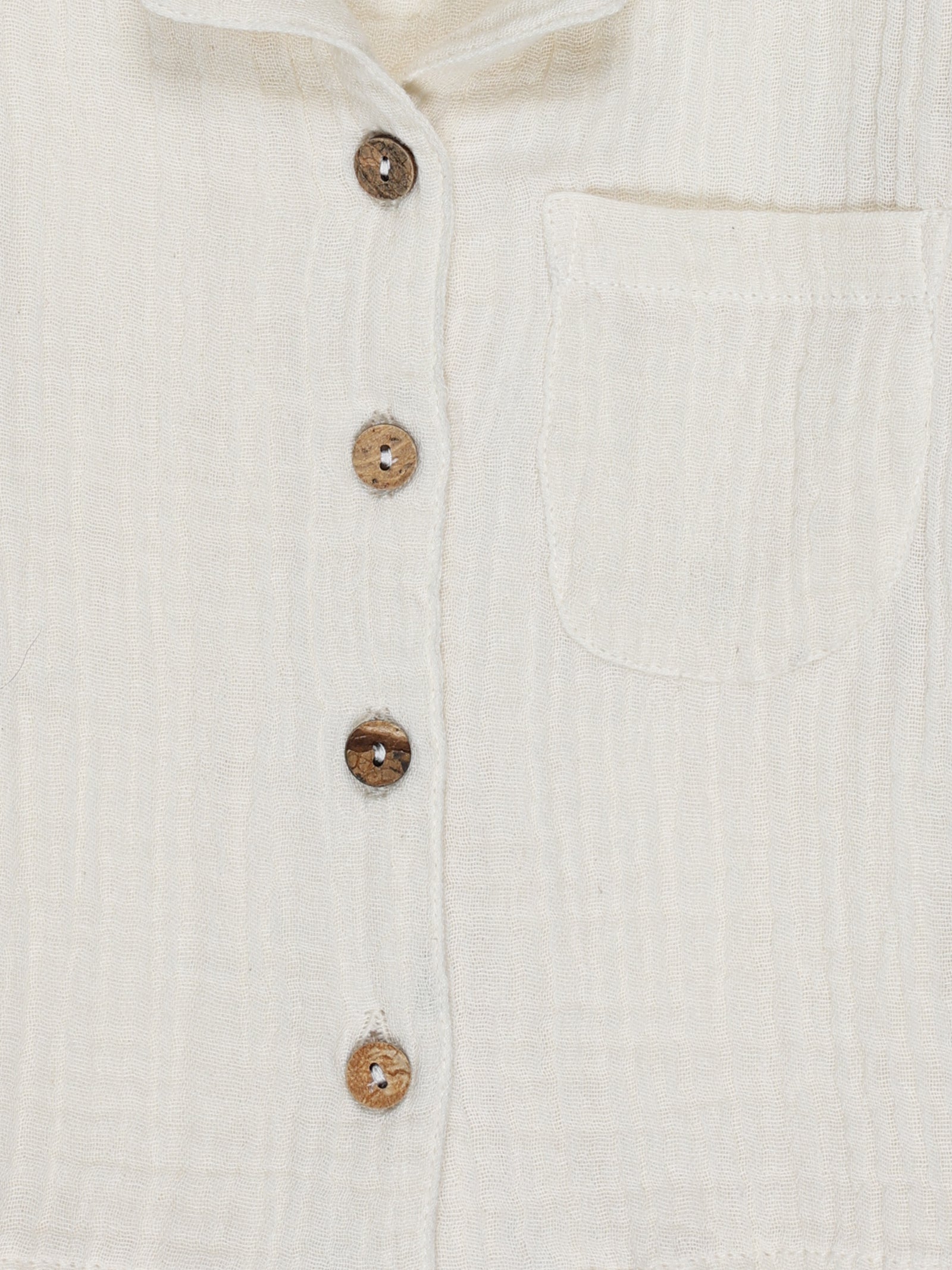 Close-up of wooden buttons and fabric texture on cream white organic cotton baby shirt – breathable and eco-friendly by Ray&Baby.